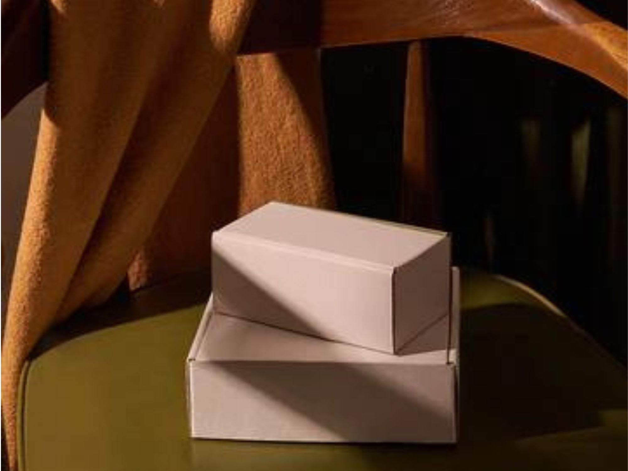 pleasure gap will always ship your order in plain cardboard packaging, so you don't need to worry about any nosey neighbours. The image shows 2 plain white cardboard boxes resting on a chair.